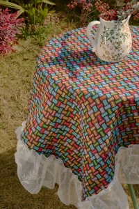 Detail of colorful woven plaid tablecloth with elegant white floral lace edge detail