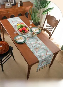 Detail of light blue jacquard table runner with traditional landscape embroidery and tassels