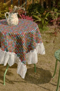 Detailed texture of colorful plaid tablecloth with elegant white lace ruffle edges
