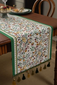 Detail of floral and bird jacquard pattern with fringe tassels on a table runner