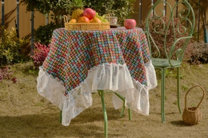 Close-up of colorful geometric checkered tablecloth with elegant white floral lace edges
