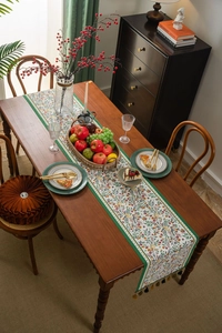 Close-up of floral table runner with green borders and decorative tassel edge details