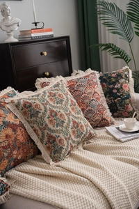 Detail of American jacquard floral pillow cases with fringe tassels on a knit blanket