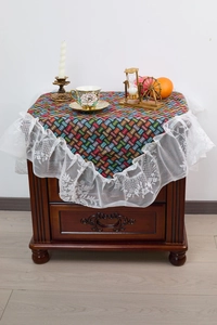 Detail of colorful geometric woven tablecloth with elegant white lace floral embroidery