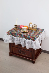 Detail of colorful geometric woven tablecloth featuring elegant white floral lace ruffle edges