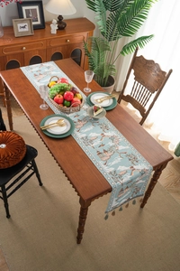 Detail of light blue Chinese table runner with traditional landscape pattern and grey tassels
