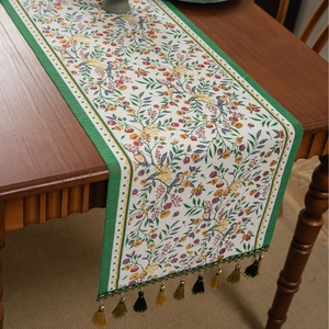 Detail of floral bird jacquard table runner with dark green borders and tassels