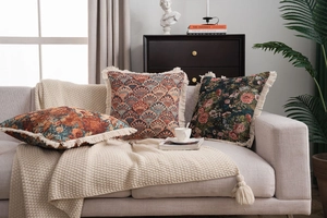 Close-up of vintage jacquard decorative throw pillow with intricate beige fringe edges