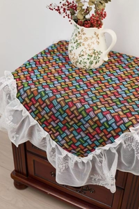 Detailed view of colorful jacquard woven fabric tablecloth with delicate white lace edges