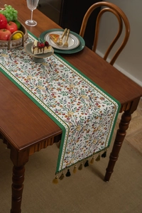Detailed shot of green jacquard table runner with berry patterns and colorful tassels