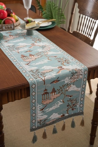 Detailed view of teal Chinese table runner with landscape jacquard pattern and tassel trim