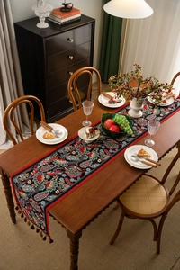 Close-up of vintage paisley pattern with decorative tassels on retro table runner