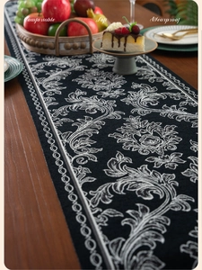 Detail of black and white jacquard table runner with vintage floral patterns for dining decor