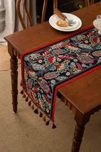 Detail of bohemian jacquard table runner with floral patterns and woven tassel pendants