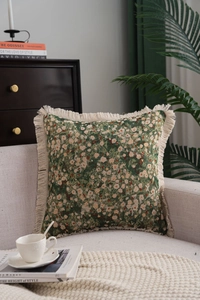 Detailed close-up of dark green floral jacquard pillow with elegant cream fringe trim