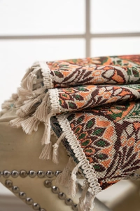 Close-up of retro ethnic jacquard blanket fabric with orange green weave and tassels