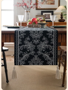 Close-up of Jacquard table runner with white damask pattern and elegant white tassels