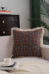 Detail of bohemian jacquard throw pillow with fringes on a cozy gray sofa setting