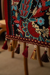 Close-up of retro jacquard table runner featuring classic floral patterns and tassel trim