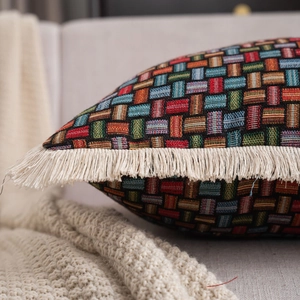 Detail view of woven bohemian cushion featuring colorful geometric patterns and cream tassels