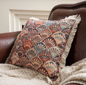 Close-up of Art Deco jacquard throw pillow with orange teal pattern and beige fringe