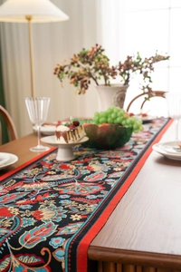 Detail of Jacquard table runner with vintage floral patterns and red piping finish