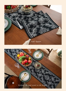 Close-up of black and white damask table runner with elegant white tassels on a wooden table