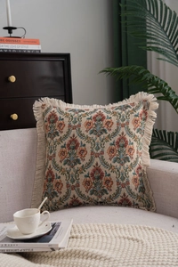 Detail of vintage floral jacquard pillow with tassel edges on a gray sofa