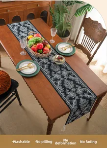Washable jacquard table runner with white floral patterns and cream tassels on wood table