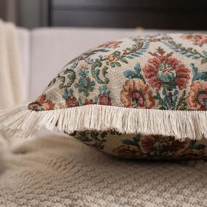 Close-up of vintage floral jacquard pillow with intricate fringe trim and rich textures
