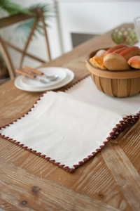Close-up of beige table runner featuring coffee brown crochet scalloped lace edging