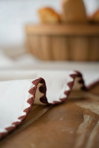 Macro detail of embroidered wavy edge on a rustic beige linen table runner