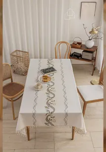 Detail of floral embroidery and elegant tassels on a cream-white linen tablecloth