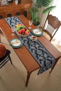 Detail of vintage black and white damask table runner with elegant white tassels on wood