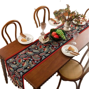 Jacquard table runner with vintage floral patterns and colorful tassels on dark wood table
