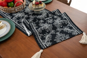 Detail of black table runner with white jacquard floral patterns and elegant tassels