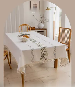 Detail of bohemian cotton linen tablecloth featuring floral embroidery and beige tassels