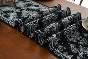 Detailed view of jacquard table runner with black and white damask patterns on wood table