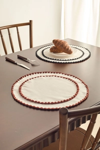 Close-up of cream cotton linen placemats with delicate scalloped crochet lace borders