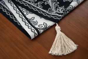 Detail of Zen style black and white jacquard table runner with beige tassel edges