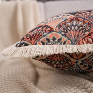 Bohemian jacquard throw pillow with cream tassels and coral pattern on knit blanket