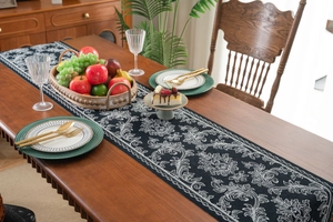 Detail of elegant black and white floral jacquard table runner on dark wood dining table