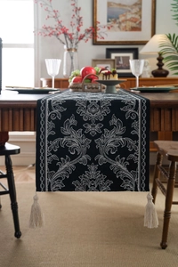 Close-up of black and white damask jacquard table runner with handmade cream tassels