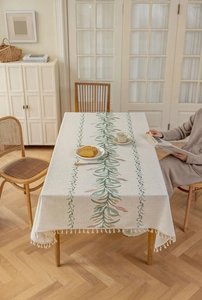 Detail der Tischdecke mit grünen Rankenmustern und cremefarbenen Quastenrändern
