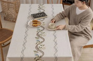 Detail of embroidered floral patterns and tassel edges on cream linen tablecloth