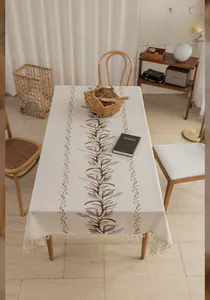 Detail of cream linen tablecloth with vine embroidery and decorative fringe edges