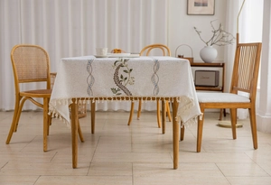 Detail of floral embroidery and fringe tassels on a beige linen tablecloth for dining tables