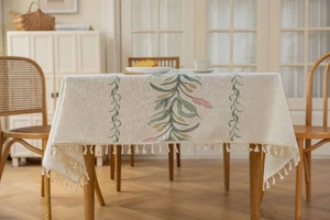 Nahaufnahme der beigen Leinentischdecke mit Olivenblatt-Stickerei und Quastenrand