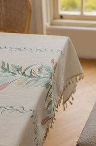 Detailaufnahme der beige Leinentischdecke mit Tulpenstickerei und Quastenverzierung