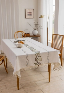 Close-up of elegant floral vine embroidery and tassel edge on linen tablecloth